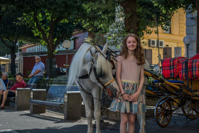 Portrait of girl standing against horse