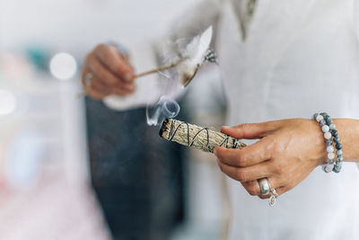 Cropped hand of woman holding feather and sage