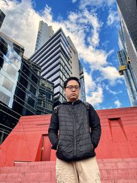 Portrait of young woman standing against building