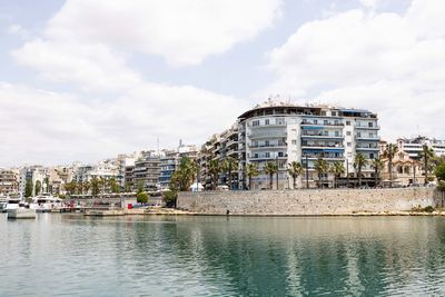 Buildings by river against sky