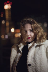 Portrait of woman standing outdoors at night