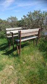 Empty bench on field against sky