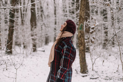 Rear view of woman standing in forest during winter