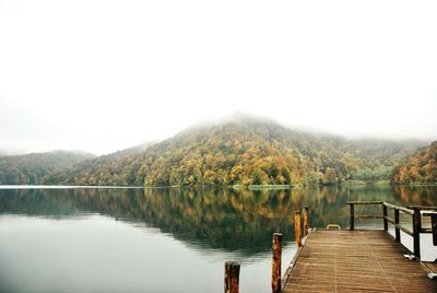 Pier in calm lake against clear sky