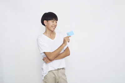 Portrait of smiling young woman standing against white background