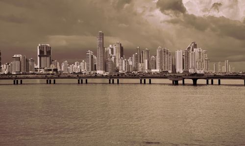 Pier over sea by buildings against sky in city