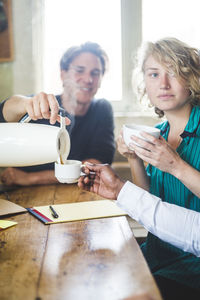 Male computer programmer serving hot coffee to colleague at desk in office