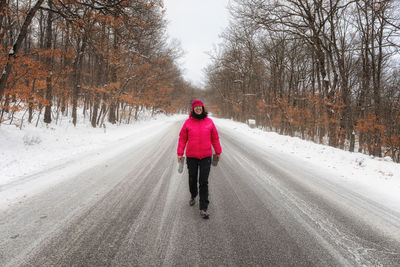 Woman walking on snow covered road during winter