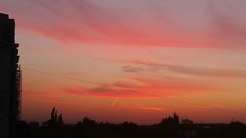 Low angle view of electricity pylon at sunset