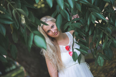 Young woman smiling by tree