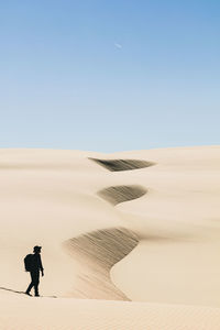 Man walking in desert against clear sky