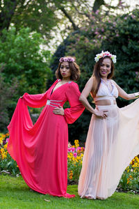 Portrait of fashion models holding long dress against trees at park