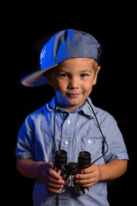 Portrait of boy standing against black background