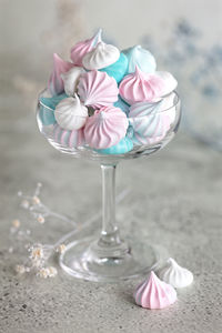 Homemade pastel pink, blue and white meringue in glass on neutral grey background. 