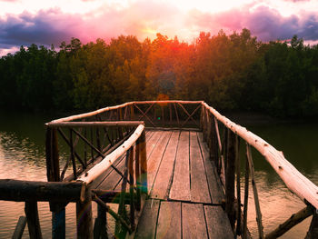 Pier over lake against sky during sunset