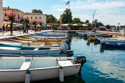 Boats moored at harbor against sky in city