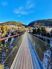 Footbridge over mountain against blue sky