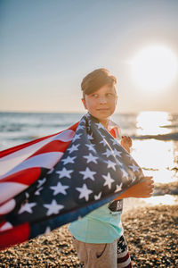 Man holding flag at beach against sky