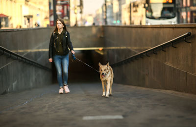 Woman with dog standing in city
