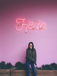 Portrait of happy young woman standing against pink sky