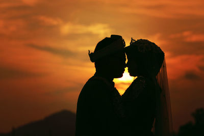 Close-up of silhouette couple against orange sunset sky