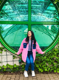 Young lady in pink jacket at the rooftop of warsaw university library near green round window 