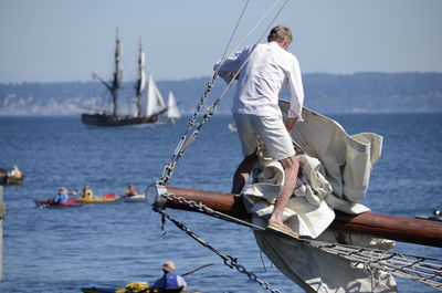 Man on boat sailing in sea against sky