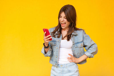 Portrait of smiling young woman against yellow background