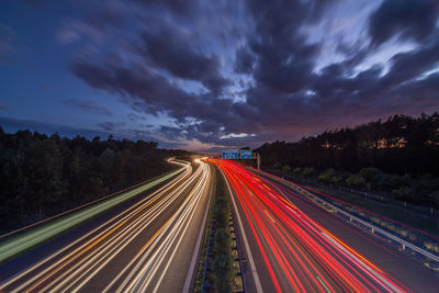 Light trails on road against sky at night