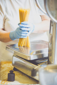 Midsection of woman packing spaghetti in factory