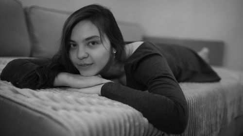 Portrait of young woman sitting on sofa at home