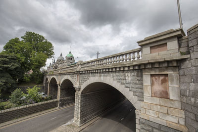 Arch bridge against sky in city