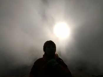 Rear view of woman against sun in sky during foggy weather