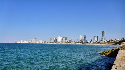 Sea and cityscape against clear blue sky