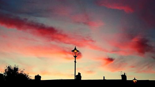 Low angle view of silhouette street light against dramatic sky