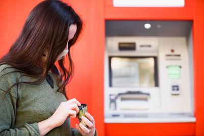 Woman wearing mask standing against atm machine