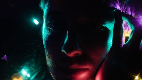 Close-up portrait of man in illuminated lights