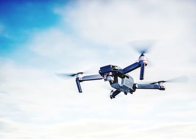 Low angle view of drone flying against sky