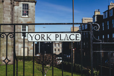 Information sign by buildings in city against sky