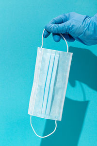 Close-up of hand holding blue over white background
