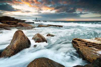 Man standing on rock at beach against sky