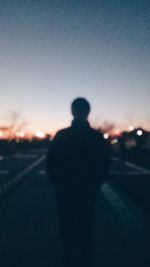 Rear view of silhouette man standing on road against sky