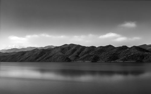 Scenic view of lake by mountains against sky