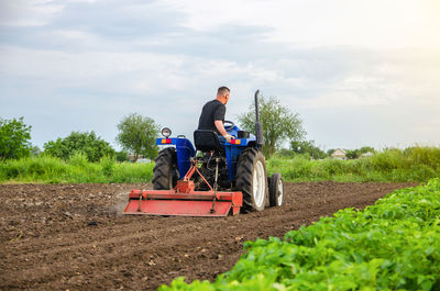 A farmer is cultivating a farm field. milling soil, crushing before cutting rows. loosening 