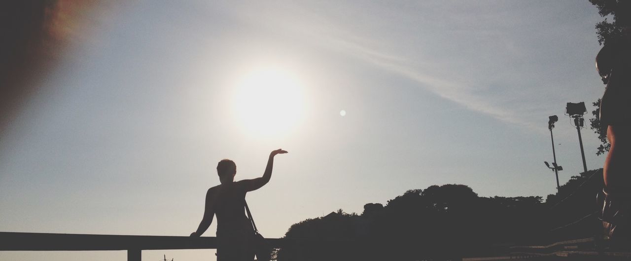 silhouette, lifestyles, sunset, leisure activity, men, sun, standing, sky, outline, sunlight, side view, low angle view, full length, outdoors, clear sky, person, dusk, back lit