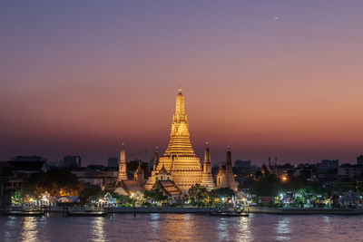 Illuminated buildings against sky at sunset