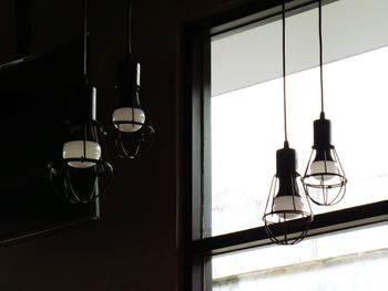 Low angle view of illuminated light bulb hanging from ceiling