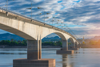 Bridge over river against cloudy sky