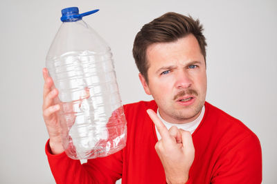 Portrait of woman holding bottle against white background