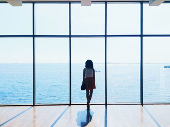 Rear view of woman standing in building against sea